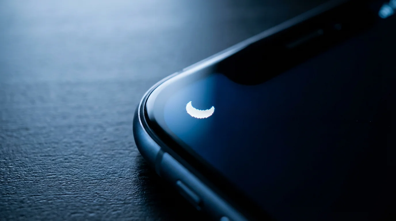 Close-up macro photo of a smartphone screen displaying a tiny 'Do Not Disturb' icon during blue hour.