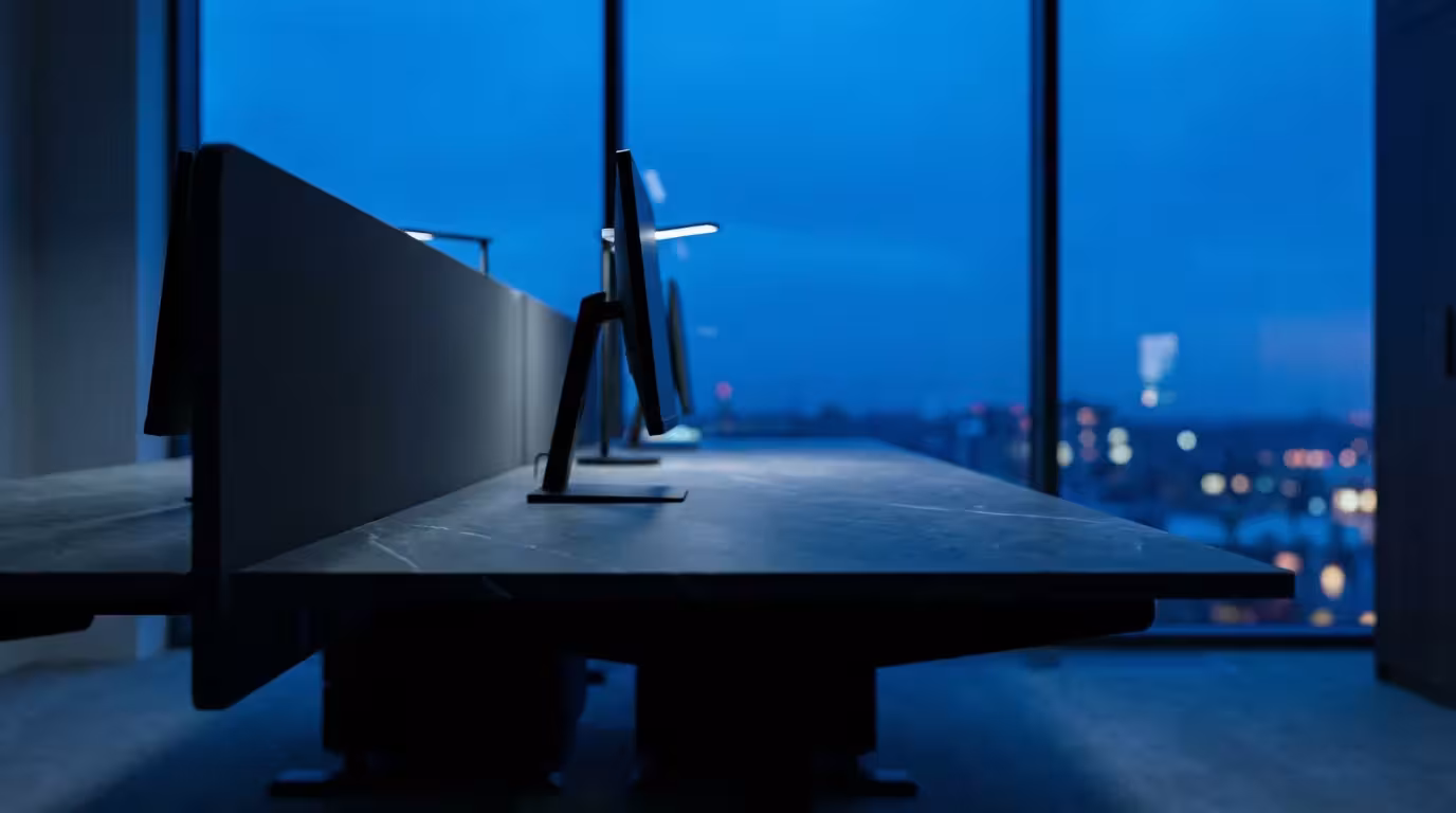 Low angle view of a clean minimalist workspace silhouette against a blue hour city window.