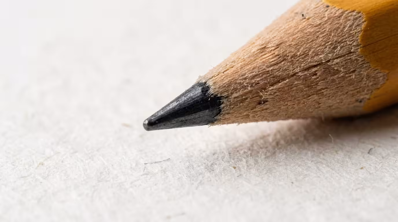 Macro closeup of sharp pencil tip over paper representing focus and time blocking.