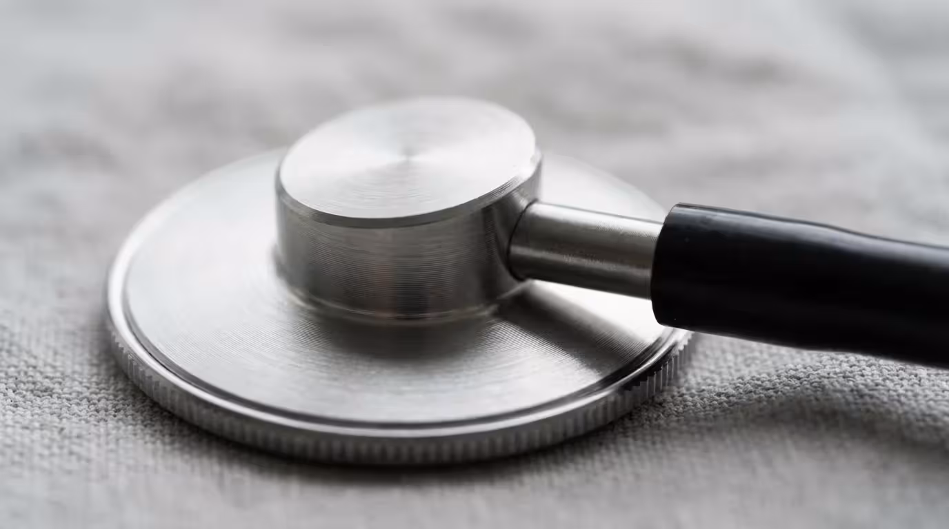 Macro photograph of a stethoscope chest piece on linen representing professional medical advice.