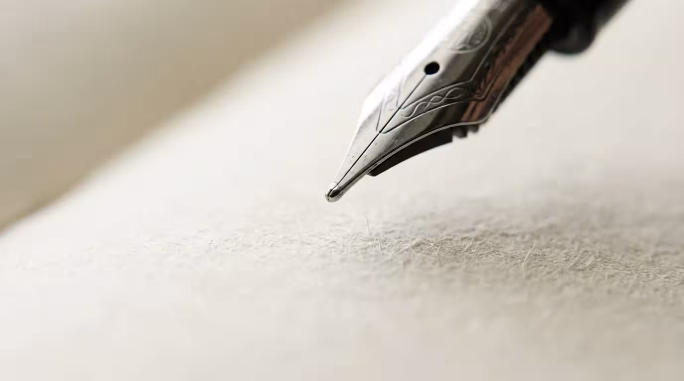 Macro photography close-up of a fountain pen nib over blank paper representing focus.