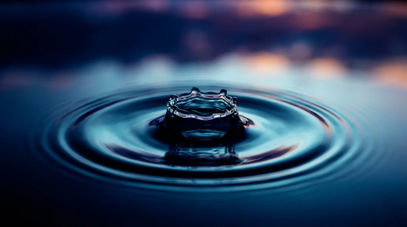 Macro photography of a water drop creating a ripple effect in blue light.
