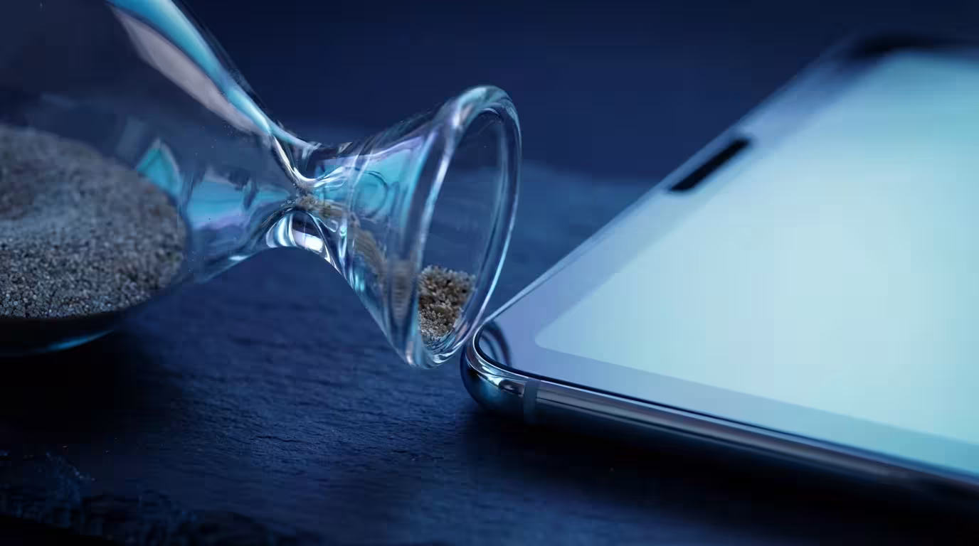 Macro photography of an hourglass next to a tablet device in cool blue lighting