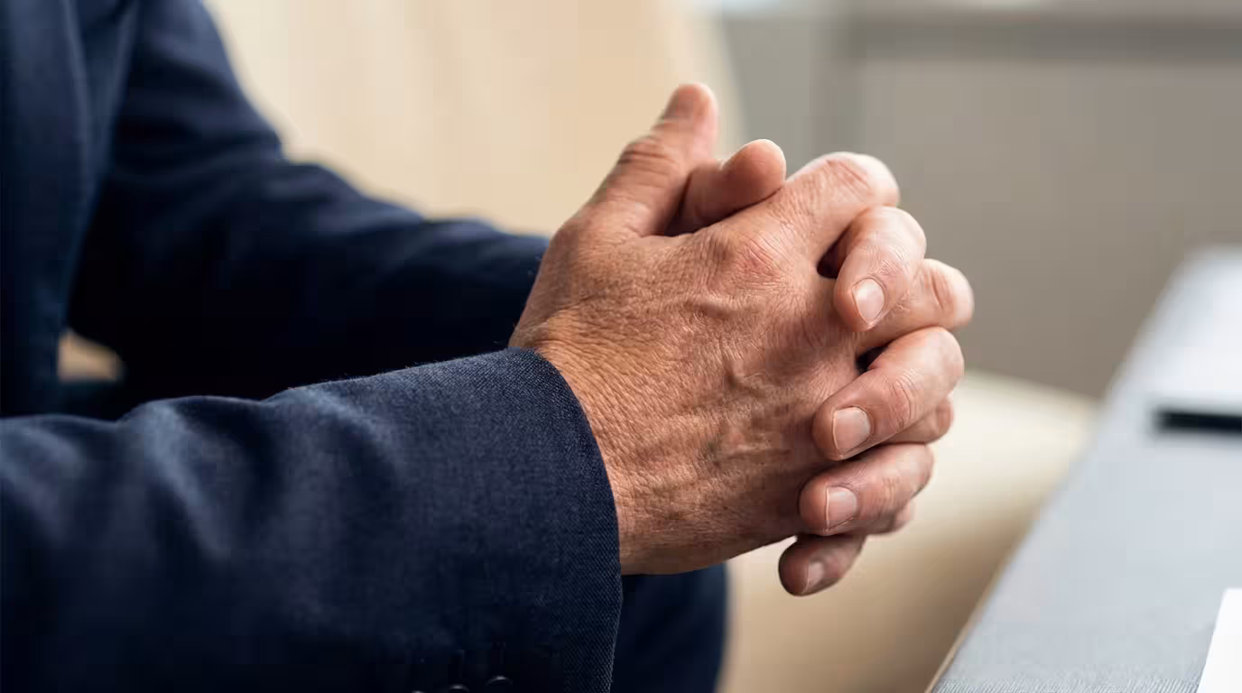 Macro photography of professional hands resting on navy suit fabric during mental preparation.