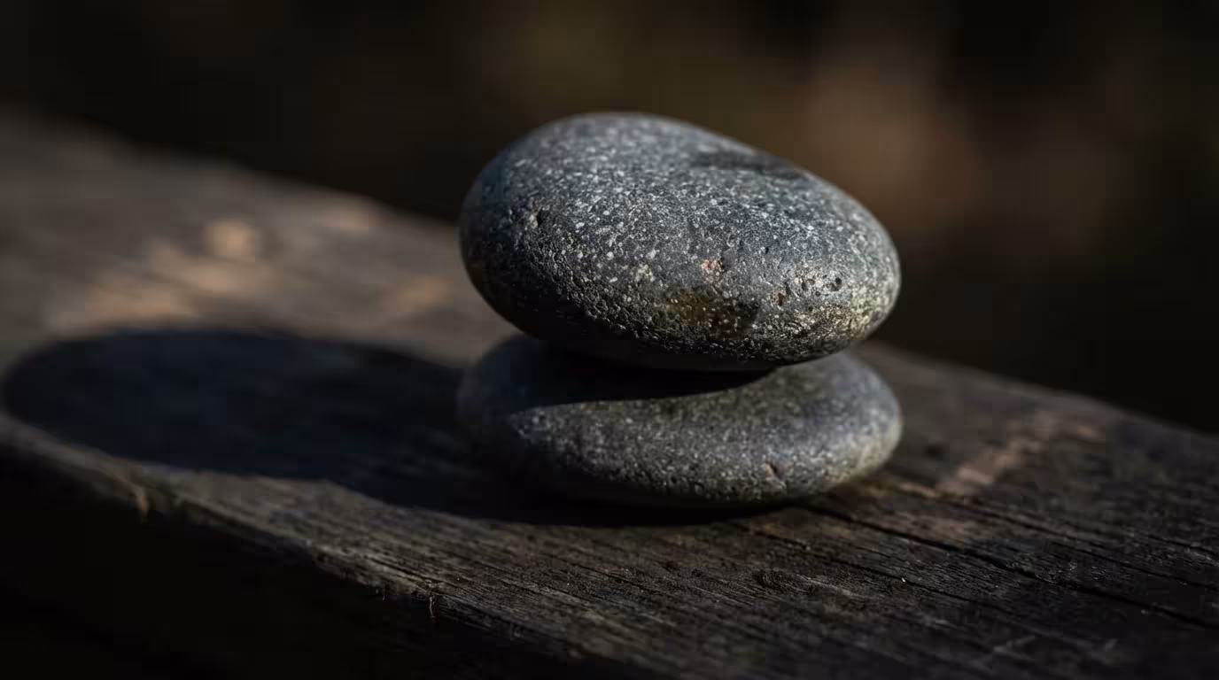 Macro photography of stacked balanced stones in dramatic afternoon shadow lighting.