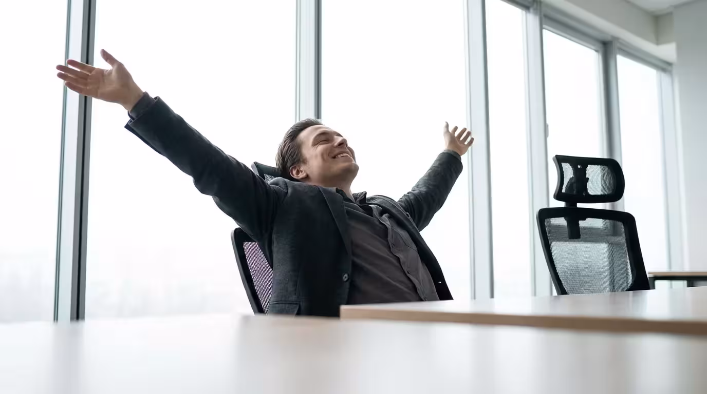 Professional stretching in office chair with a smile, celebrating a moment of productivity success.
