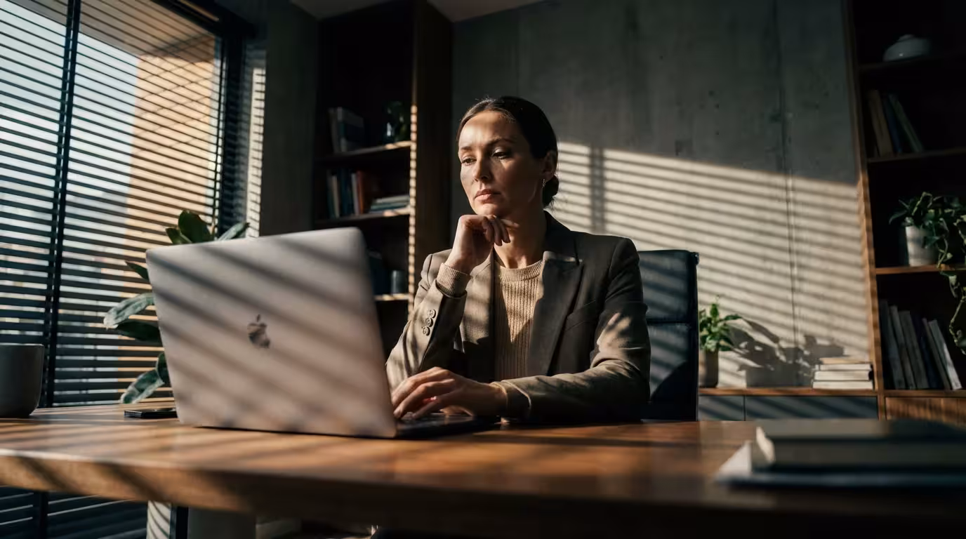 Woman at desk in home office with dramatic afternoon shadows.